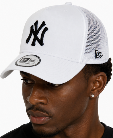 A man wearing a white New York Yankees trucker hat, shown in side profile and back view against a light gray background.