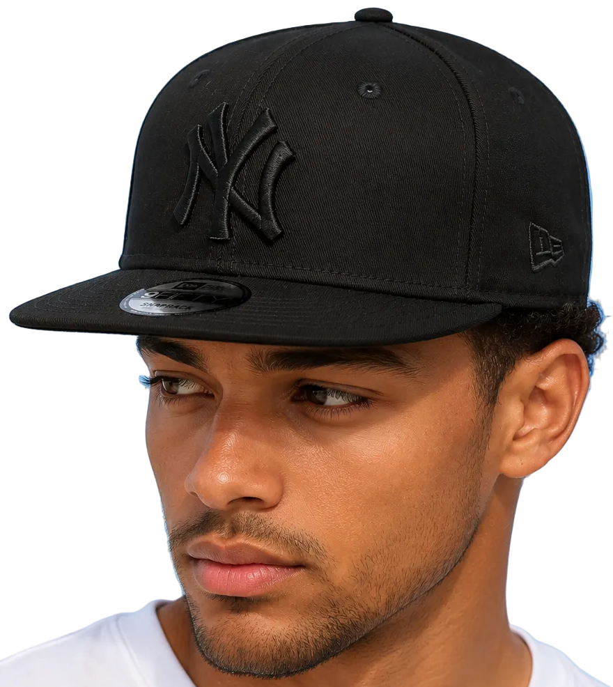 A man wearing a black New Era 59FIFTY snapback cap with an all-black embroidered New York Yankees logo on the front and a small black New Era flag on the side, set against a plain white background.