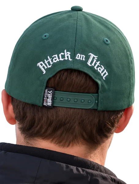 Two people seen from behind wearing matching green baseball caps with 'Attack on Titan' embroidered in white on the back, set against a blue sky.