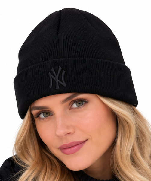 A man and a woman wearing matching black knit beanie hats with a dark gray embroidered New York Yankees logo on the front, set against a plain white background.