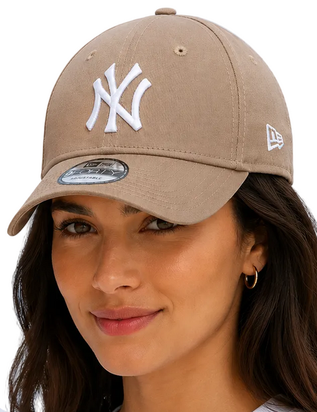 a woman wearing matching tan New York Yankees baseball caps with white embroidered logos, posed against a light blue background.