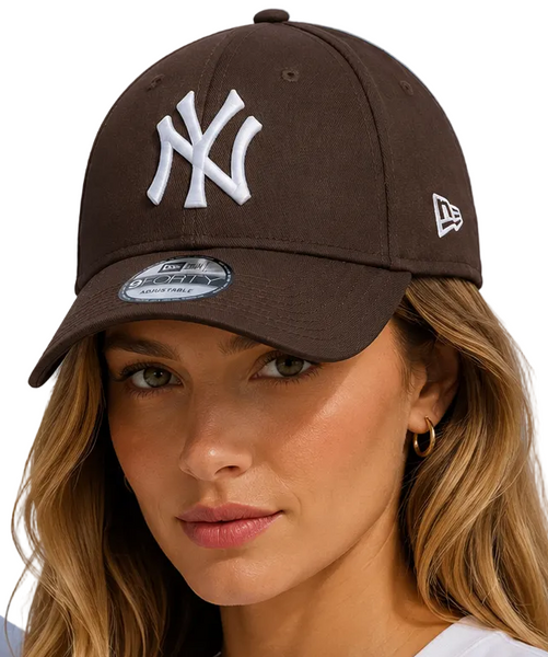 A man and a woman wearing dark brown New Era 9FORTY baseball caps with a white New York Yankees logo, set against a bright blue sky background.