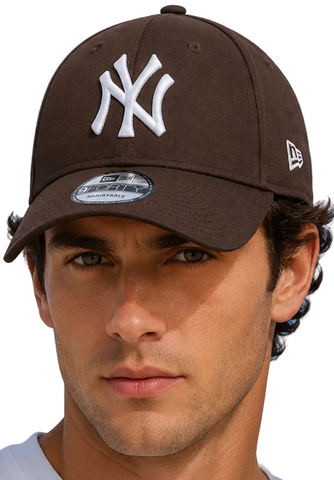 A man and a woman wearing dark brown New Era 9FORTY baseball caps with a white New York Yankees logo, set against a bright blue sky background.