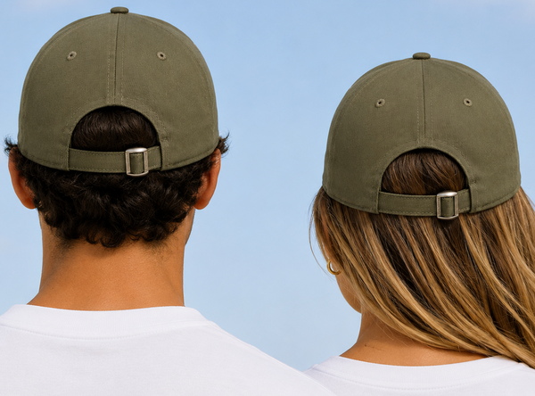 Two people shown from behind wearing matching olive green baseball caps with adjustable back straps, set against a clear blue sky.